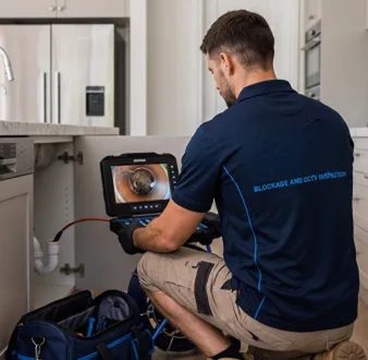 Plumber clearing a blocked toilet in a Canada Bay bathroom